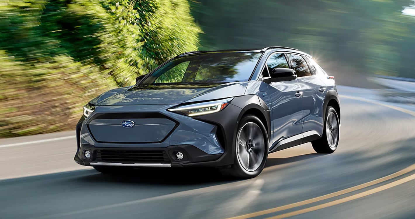 Subaru Solterra SUV in blue driving on scenic road