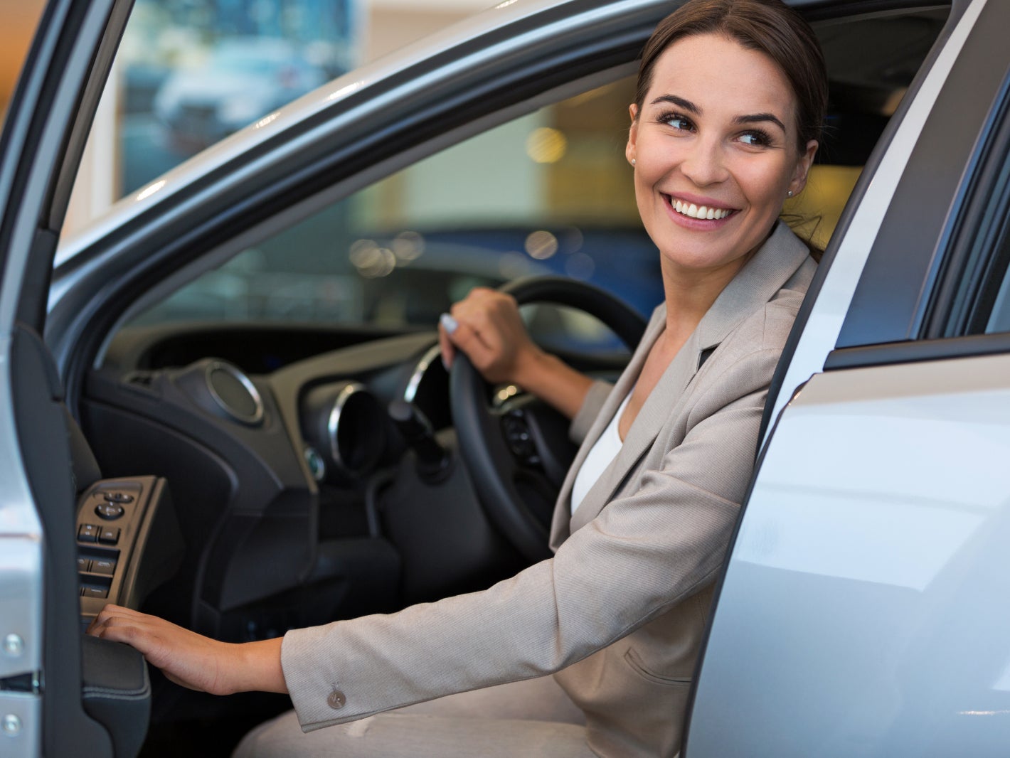 Woman smiling inside her Subaru while opening the door