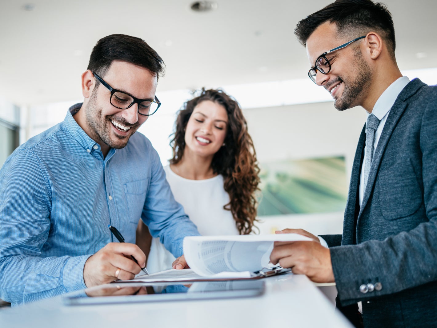 Customers signing paperwork while speaking with a Subaru sales associate