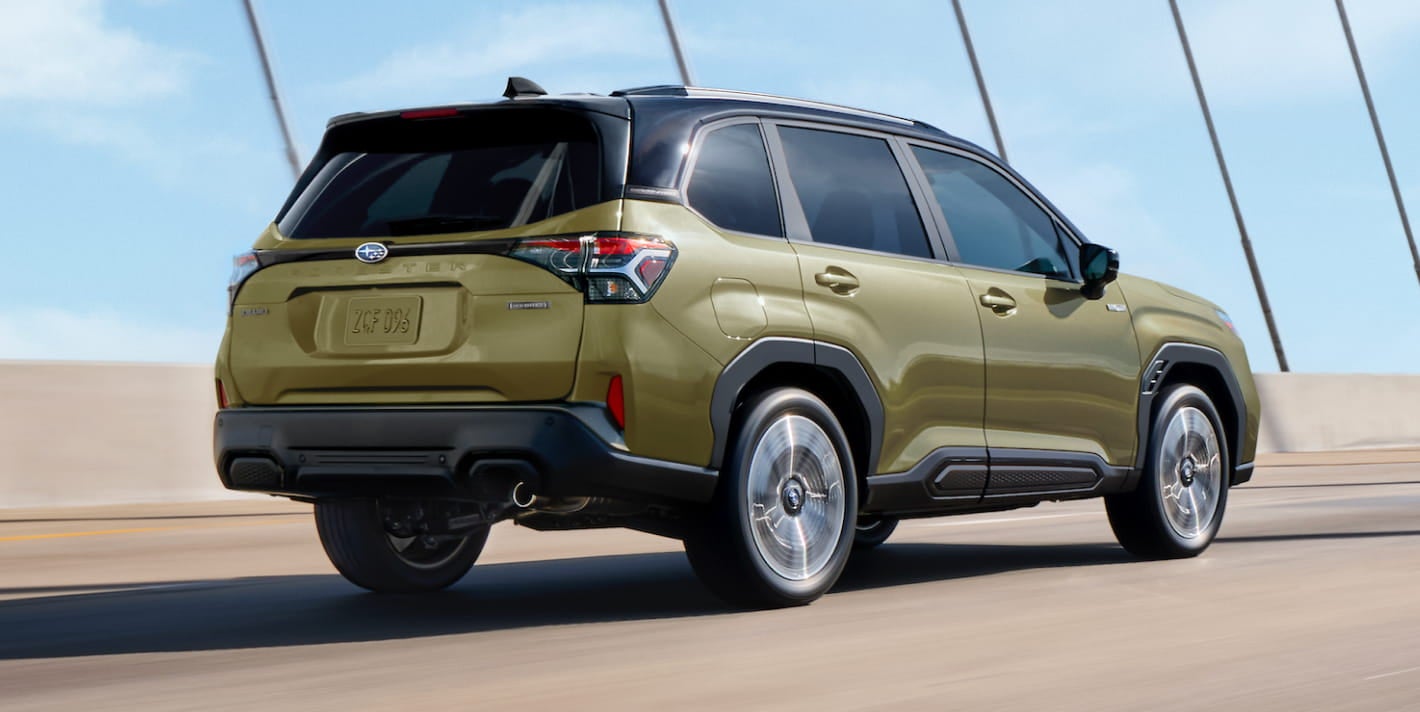 Green Subaru Forester Hybrid driving across a bridge, shown from the rear three-quarter view.