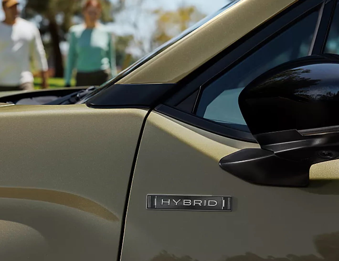 Close-up of a green Subaru Forester Hybrid showing the Hybrid badge and side mirror.