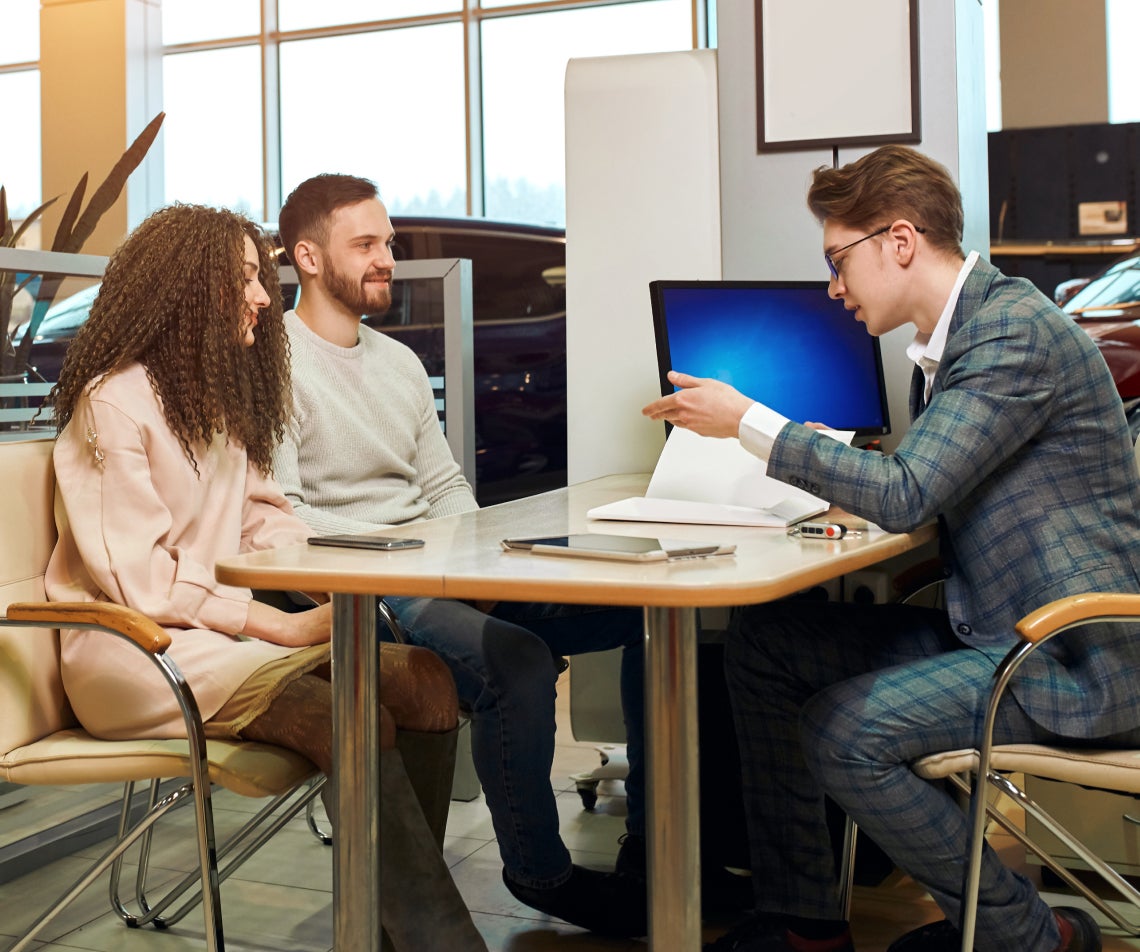 Customers speaking with a Subaru sales associate over paperwork